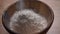 Flour falling into wooden bowl