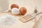 Flour, glass of milk, whisk and eggs on wooden table