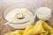 Flour mixture with butter for muffins, spoon in bowl, striped napkin, cup of milk on table