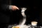 Flour is poured through a sieve on a dark background. Making dough for cooking