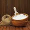 Flour in wooden bowl and wheat in burlap bag.