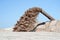 The flow of brown liquid from the pipe on the background of a pile of sand and blue clear sky