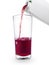 The flow of pomegranate juice being poured from box into glass isolated on white background