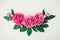 Flower border composition made of bright pink buds peony bouquet on a white wooden background. Floral texture mockup. Flat lay,