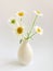 Flower composition. High key photography with white chamomile in a clay vase on a white background