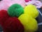 Flower craft made of green, red, yellow and pink pompoms close up