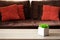 Flower pot on wooden table against defocused sofa with pillows. Front view. Soft focus. Template. Copy space