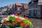 Flower pots at the edge of the canal on a sunny day in Ghent, Belgium, Europe. Nice view of picturesque medieval houses on the