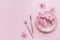 Flower and table settings overhead composition on light pink background. Pink ceramic plates, cutlery and perple orchid flowers.