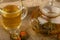 Flower tea brewed in a glass teapot, a glass of tea and balls of flower tea on a background of rough homespun fabric. Close up