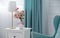 Flower vase and golden table lamp with blue armchair and curtains