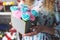 Flower Workshop: Florist girl is holding a small box with a bouquet of carnations and roses. Around on the shelves are