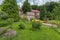 Flowerbeds with bright flowers, benches and decorative plantations on the background of a hotel complex with a red roof