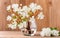 Flowering twig with white flowers in a glass vase on a wooden background