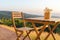 Flowerpot on wooden table and chairs on terrace. Beautiful seating with landscape mountains view while sunset