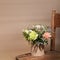 Flowers bouquet in ecological DIY cardboard vase standing on old wooden chair on beige with shadows and copy space