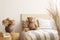 Flowers in brown vase on wooden nightstand table next to single bed with stripped bedding with teddy bear