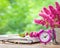 Flowers in bucket, pink alarm clock and book