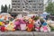 Flowers and children toys at the place where the children died. In the background, a civilian building was damaged by an