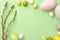 Flowers composition. Blossoming branch, eggs and ceramic rabbits on green pastel background. Spring, easter concept. Flat lay, top