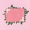 Flowers composition. Pink blank paper, white fresh roses and green leaves on gentle pink background. Flat lay, top view, copy