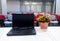 Flowers composition on table with notebook in empty conference room, office. Conference table and chairs in meeting room