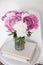 Flowers decor, fresh peonies on designer chair in white room int