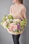 Flowers delivery. Flower arrangement in large Wicker basket. Beautiful bouquet of mixed flowers in woman hand. Floral