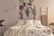 Flowers and a hummingbird painted on the fabric above a bed which is dressed in green plants pattern light color bedding in a cozy