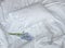 Flowers on the messy bed, white bedding items and blue flowers bouqet