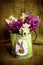 Flowers in the metal flagon decorated with illustration of Easter Bunny and Easter egg on the green bagging