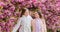 Flowers soft pink clouds. Children enjoy warm spring. Lost in blossom. Girls posing near sakura. Kids on pink flowers of