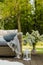 Flowers in vase next to wicker armchair on wooden terrace in green garden