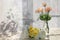 Flowers in a vase on a sunny window in a rustic house on a wooden table