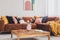Flowers in vase on wooden coffee table in fashionable living room interior with brown corner sofa with pillows and abstract