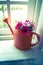 Flowers in watering can in the window