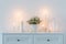 flowers in white ceramic vase with burning candles in white interior