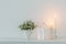 flowers in white ceramic vase with burning candles in white interior