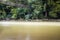 Flowing dirty river under old ruined cable bridge