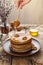 Flowing honey on stack of pancakes with nuts