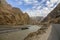 The flowing river under the snowy mountains and There is a highway by the river