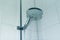 Flowing water from modern shower head at tiled bathroom interior, nobody