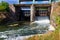 Flowing water with water spray from the open sluice gates of a small dam