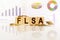 FLSA the word on wooden cubes, cubes stand on a reflective surface, in the background is a business diagram