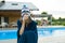 Flu, colds in the summer. Girl in a knitted hat with plaid with handkerchief sneezes, wipes her nose. Background nature, pool, gir