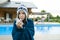 Flu, colds in the summer. Girl in a knitted hat with plaid with handkerchief sneezes, wipes her nose. Background nature, pool, gir