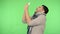 Flu symptoms. Sick young man in shirt and big warm scarf sneezing hard into napkin. green background, chroma key