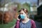 Flue and corona safety concept. Woman wearing face mask to protect herself and using smartphone. Outdoors