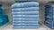 Fluffy bathing towels in blue colors stacked on shelf for sale in a store