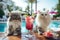 Fluffy cats drinking cold summer mocktails and relaxing by the pool. Summer vacation